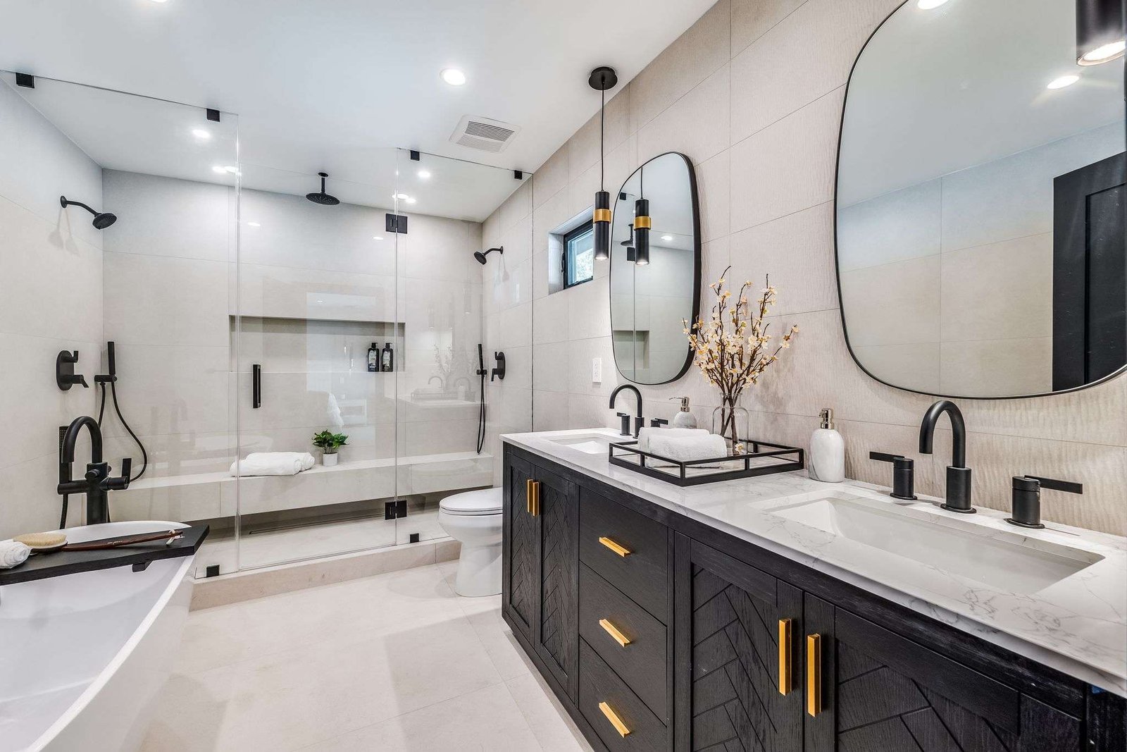 Elegant bathroom remodel with marble walls, gold fixtures, and a freestanding bathtub.
